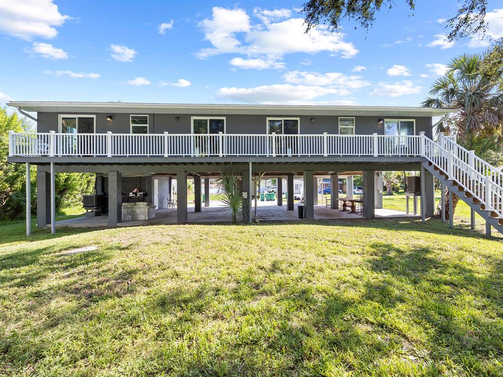 The exterior of an elevated house features a large deck with white railings and stairs — 23019 SENECA AVENUE UNIT B, PORT CHARLOTTE, FL