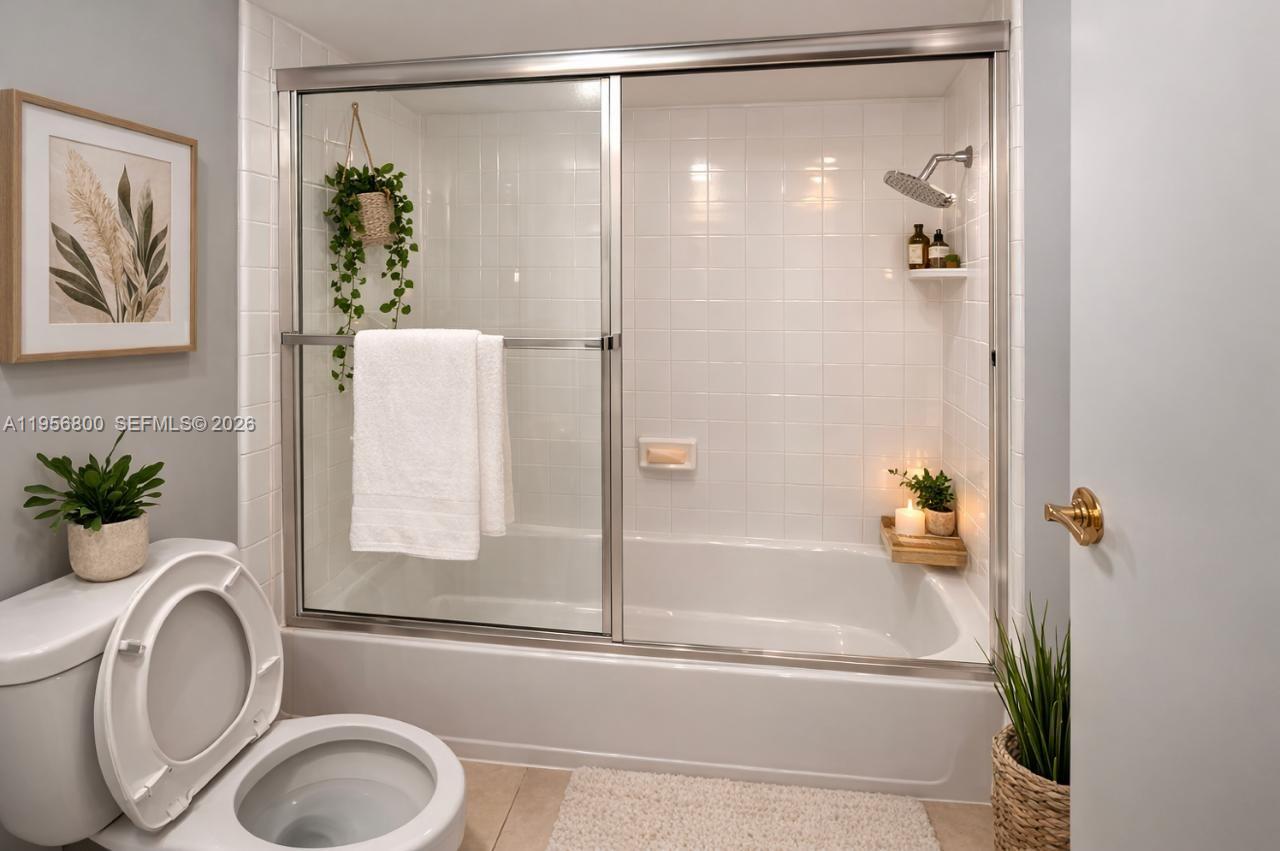 A bathroom features a white bathtub with a sliding glass door and tiled walls — 850 SW 129th Pl # 103, Miami FL 33184, MIAMI, FL