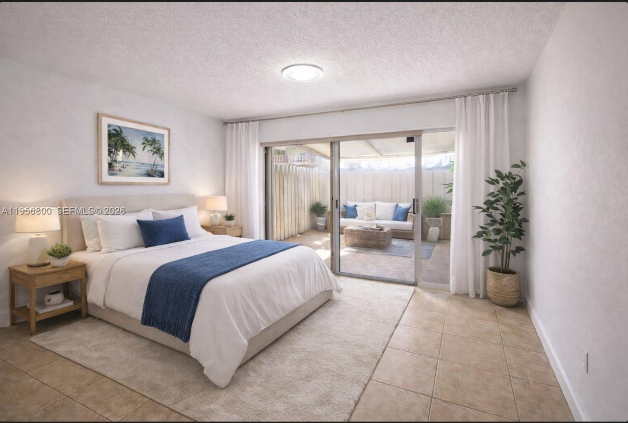 A bedroom features a bed, tile flooring, and sliding glass doors opening to a private patio — 850 SW 129th Pl # 103, Miami FL 33184, MIAMI, FL