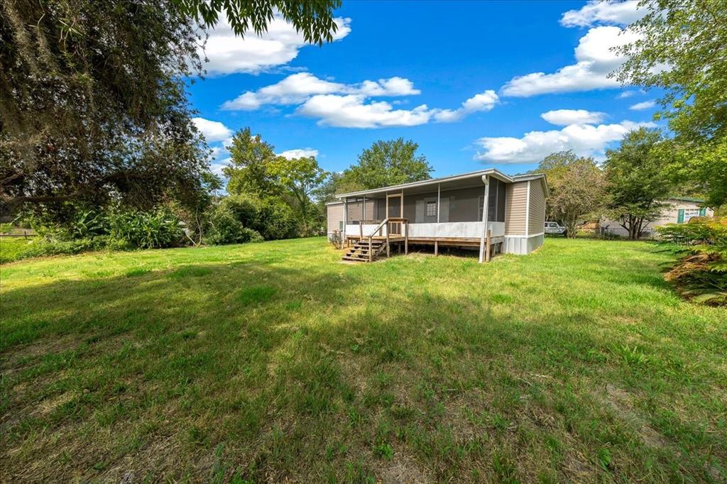 A single-story mobile home with a screened-in porch sits on a large, grassy lot — 8581 NE 147TH COURT, SILVER SPRINGS, FL