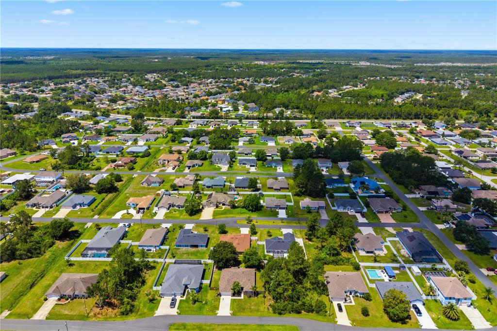 An aerial view shows a suburban neighborhood with single-family homes, green lawns, and trees — 36 LANCASTER LANE, PALM COAST, FL
