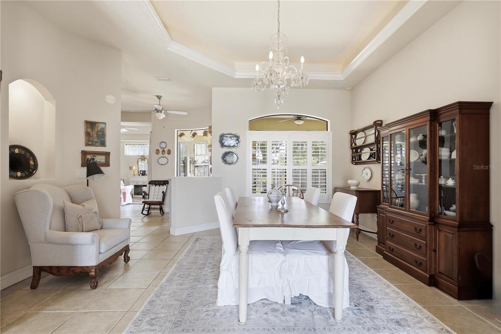 A dining room features a wooden table, white slipcovered chairs, a chandelier, and a hutch — 36 LANCASTER LANE, PALM COAST, FL