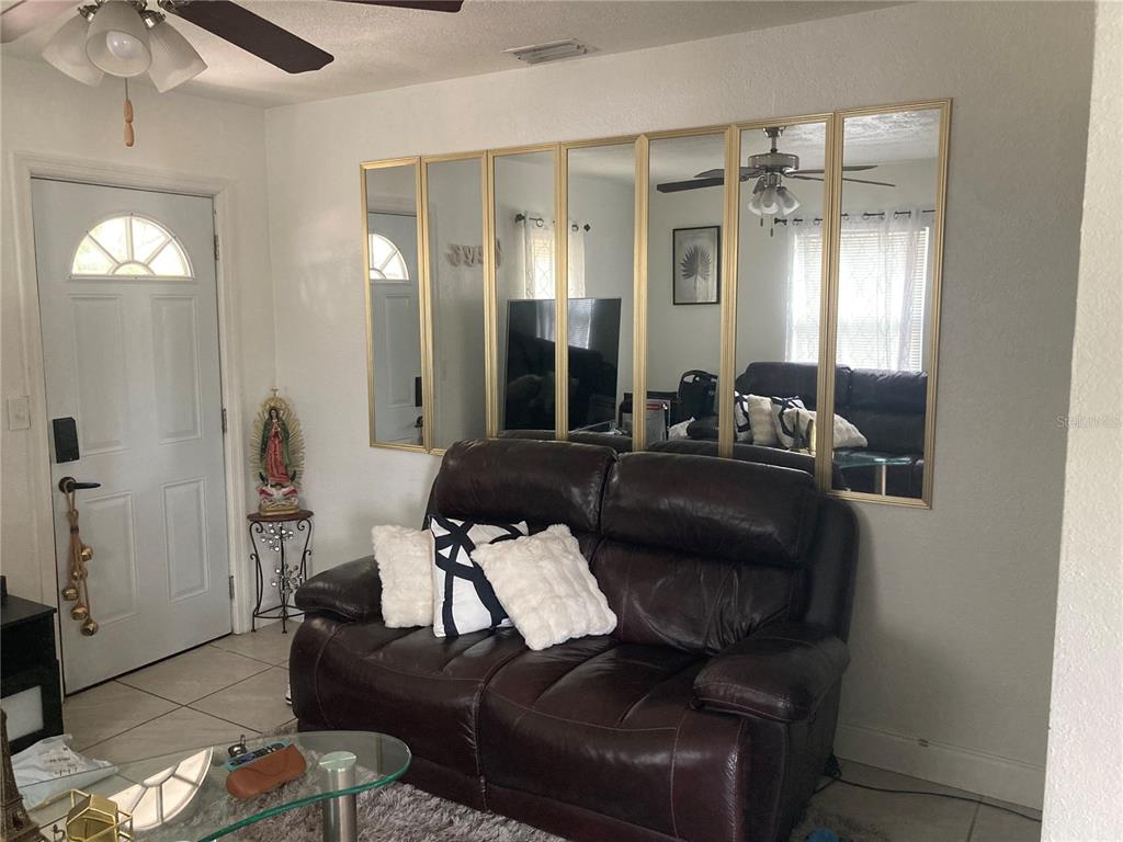 A living room features a dark leather loveseat placed against a wall with paneled mirrors — 1803 SPRINGTIME AVENUE, CLEARWATER, FL