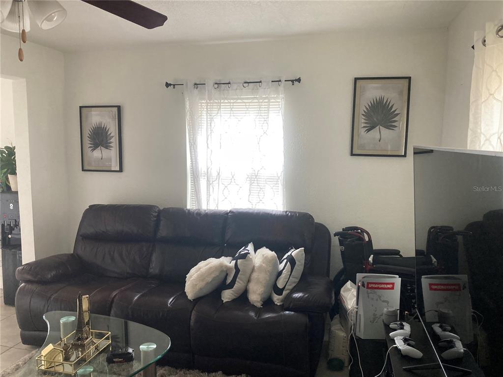 A living room features a dark leather sofa, a glass coffee table, and two framed prints — 1803 SPRINGTIME AVENUE, CLEARWATER, FL