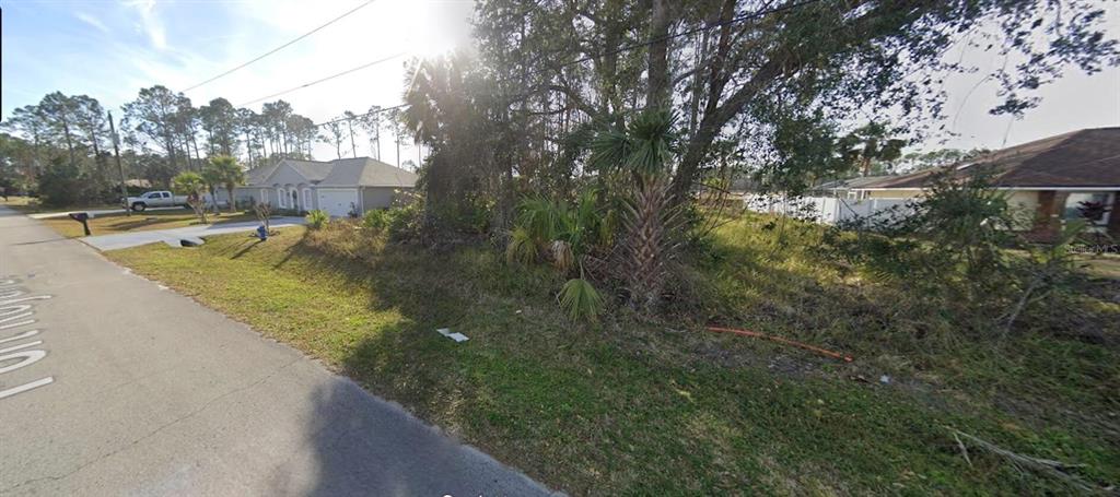 A vacant, overgrown residential lot sits between two houses on a paved suburban street — 13 PORT ROYAL DRIVE, PALM COAST, FL