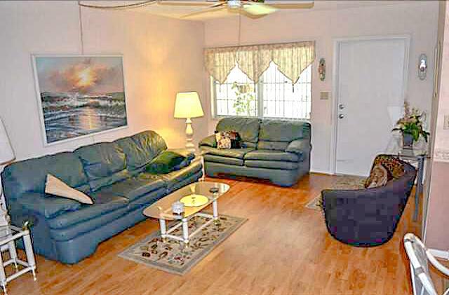 A living room features two blue leather sofas, a glass coffee table, and wood flooring — 2100 NE 38th Street # 141, Lighthouse Point FL 33064, LIGHTHOUSE POINT, FL