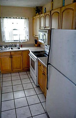 A kitchen features light wood cabinets, a white refrigerator, and a tiled floor — 2100 NE 38th Street # 141, Lighthouse Point FL 33064, LIGHTHOUSE POINT, FL
