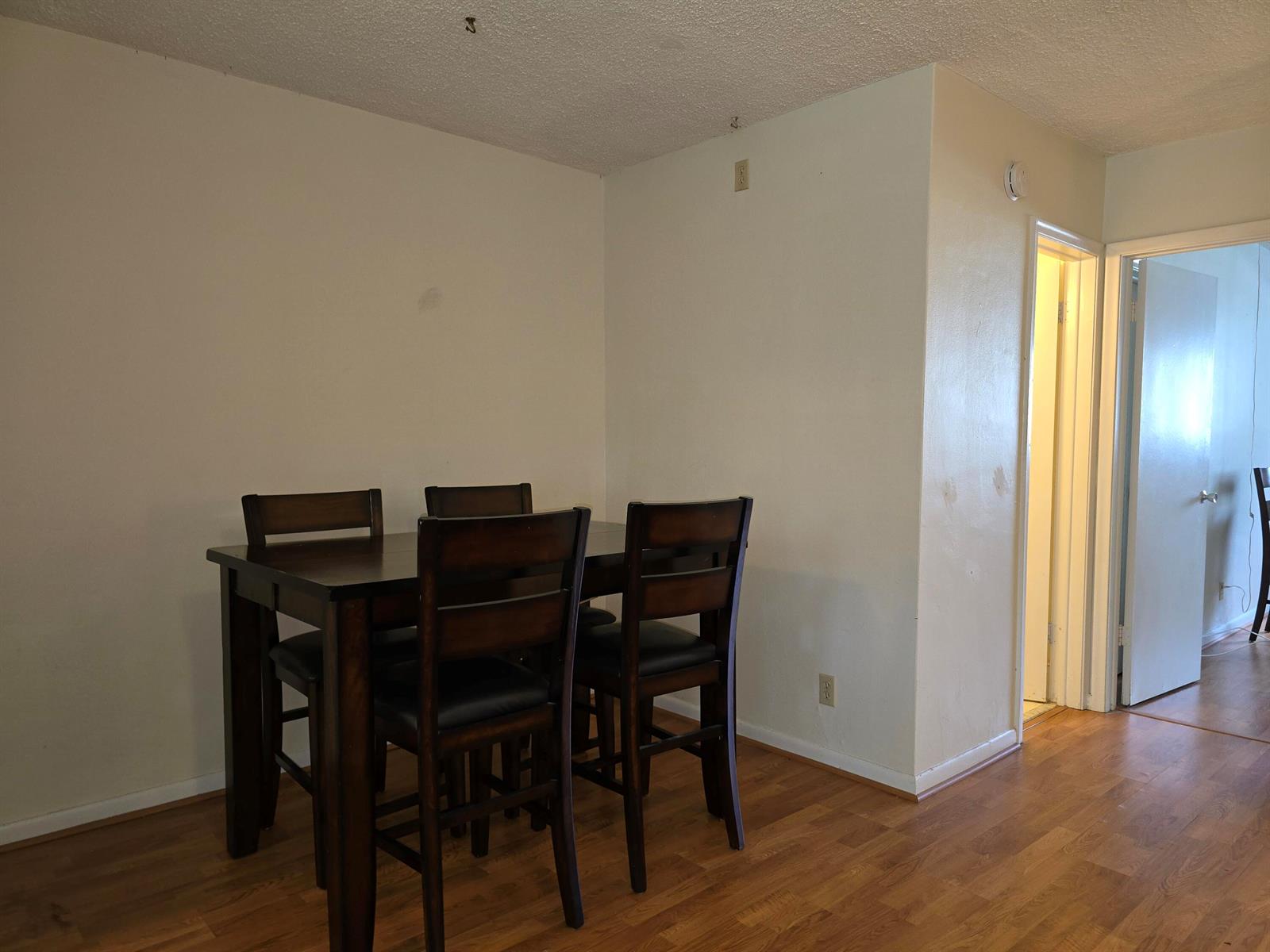 A dining area with a dark wood table and four chairs on wood-look flooring — 2100 NE 38th Street # 141, Lighthouse Point FL 33064, LIGHTHOUSE POINT, FL