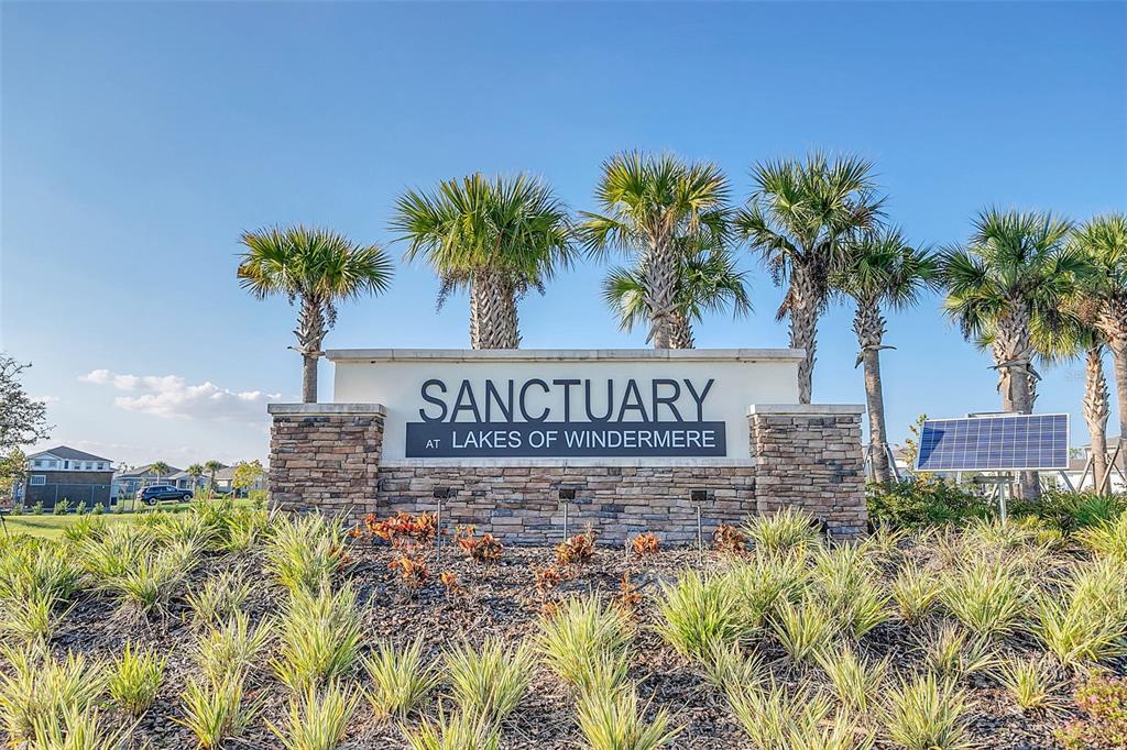A stone monument sign for Sanctuary at Lakes of Windermere stands among palm trees — 7023 KIWANO WAY, WINDERMERE, FL
