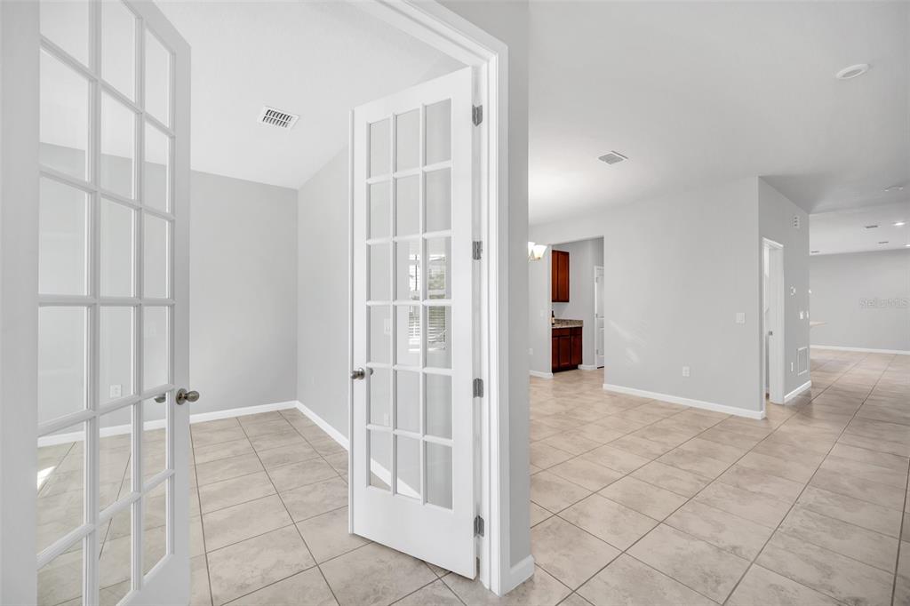 A room with French doors opens to a tiled living area and a kitchen beyond — 7023 KIWANO WAY, WINDERMERE, FL
