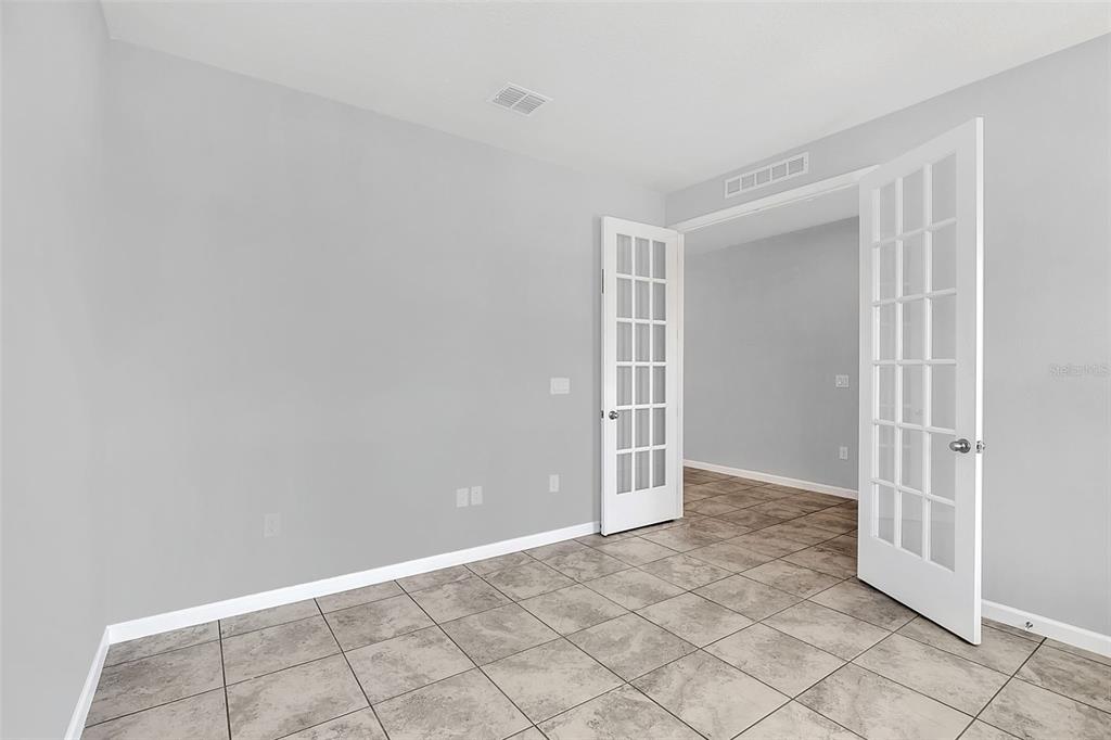 A room with gray walls, tile flooring, and white French doors leading to another space — 7023 KIWANO WAY, WINDERMERE, FL