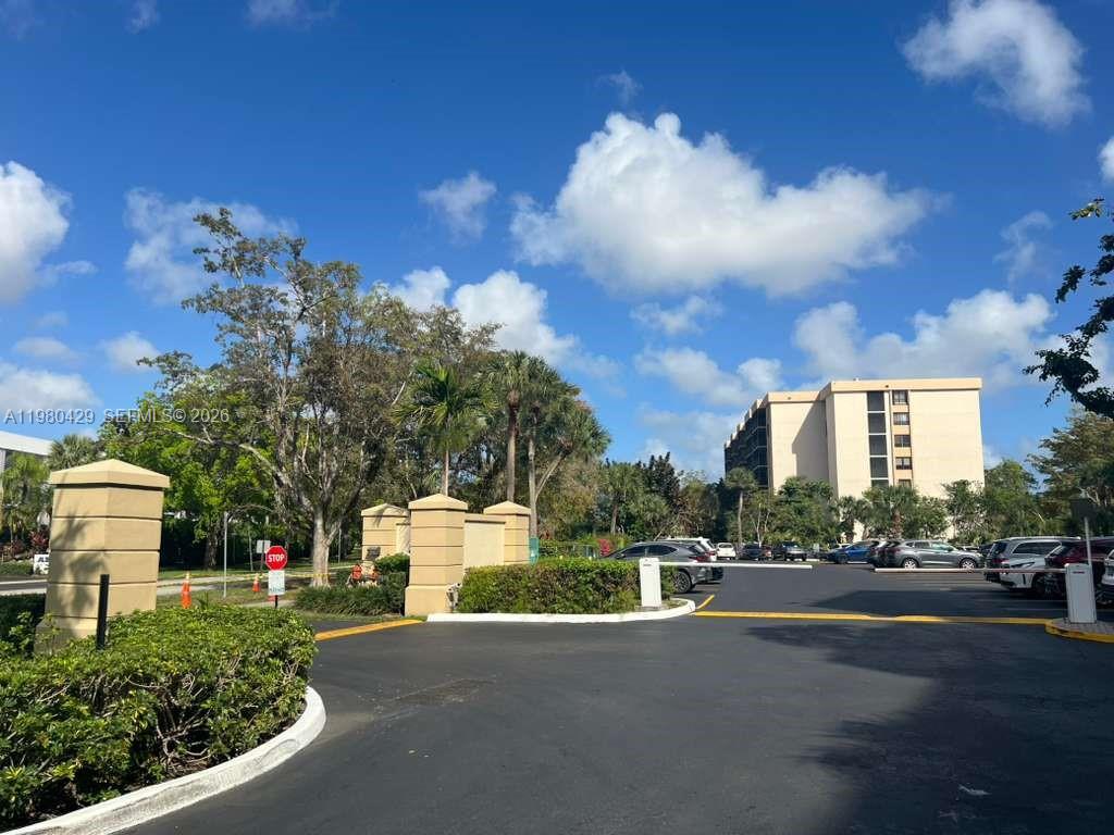 An outdoor view of a parking lot entrance with a gate and a tall building — 800 NE 195th St # 501, Miami FL 33179, MIAMI, FL