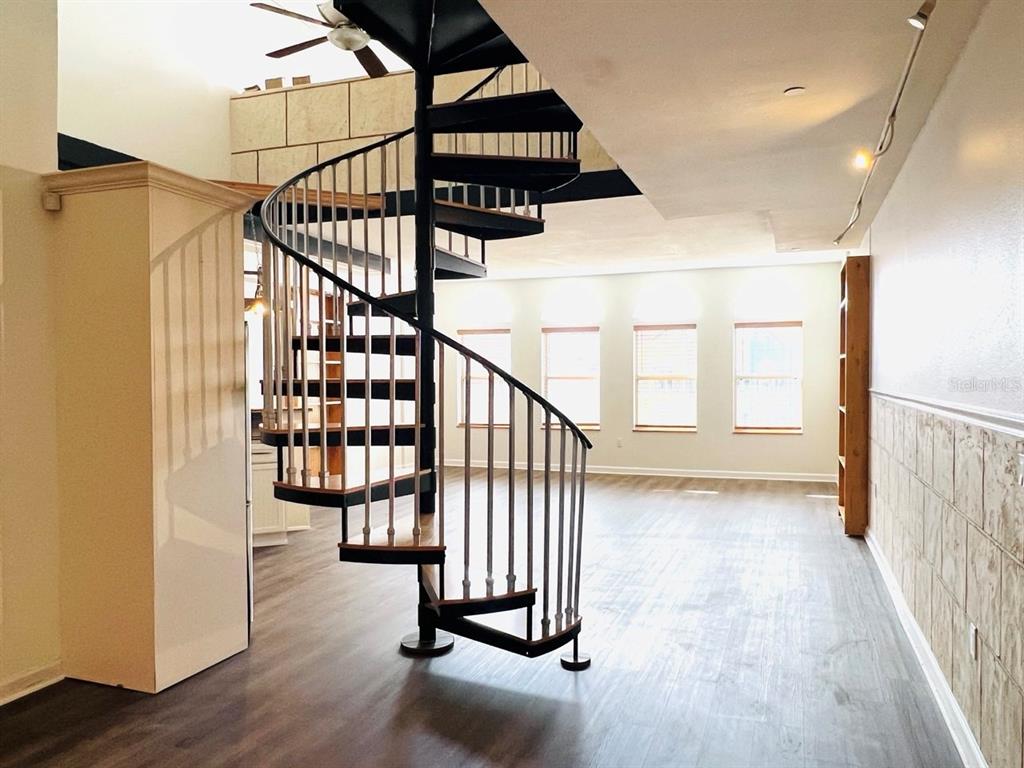 A spiral staircase stands in a room with wood-look flooring and large windows — 101 PALM HARBOR PARKWAY UNIT A404, PALM COAST, FL