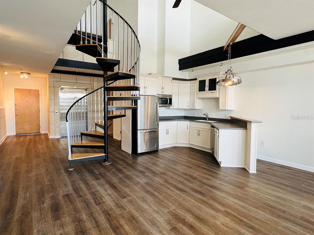 A kitchen with white cabinets and stainless steel appliances features a prominent spiral staircase — 101 PALM HARBOR PARKWAY UNIT A404, PALM COAST, FL