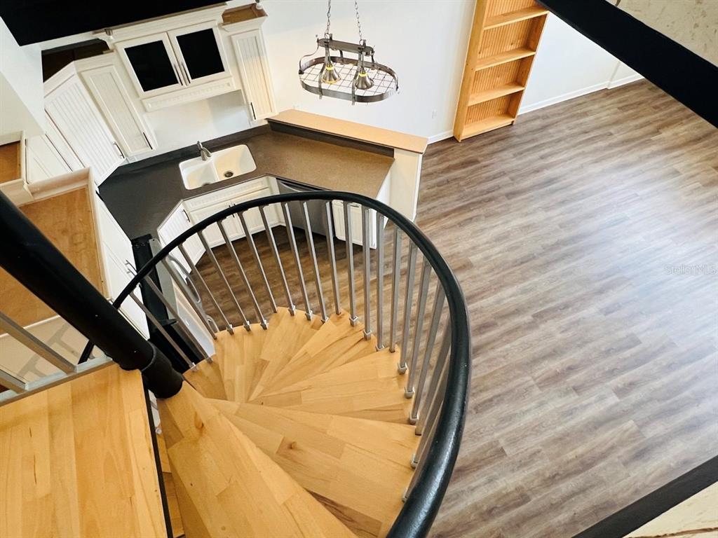 A spiral staircase overlooks a kitchen with white cabinets and wood-look flooring — 101 PALM HARBOR PARKWAY UNIT A404, PALM COAST, FL