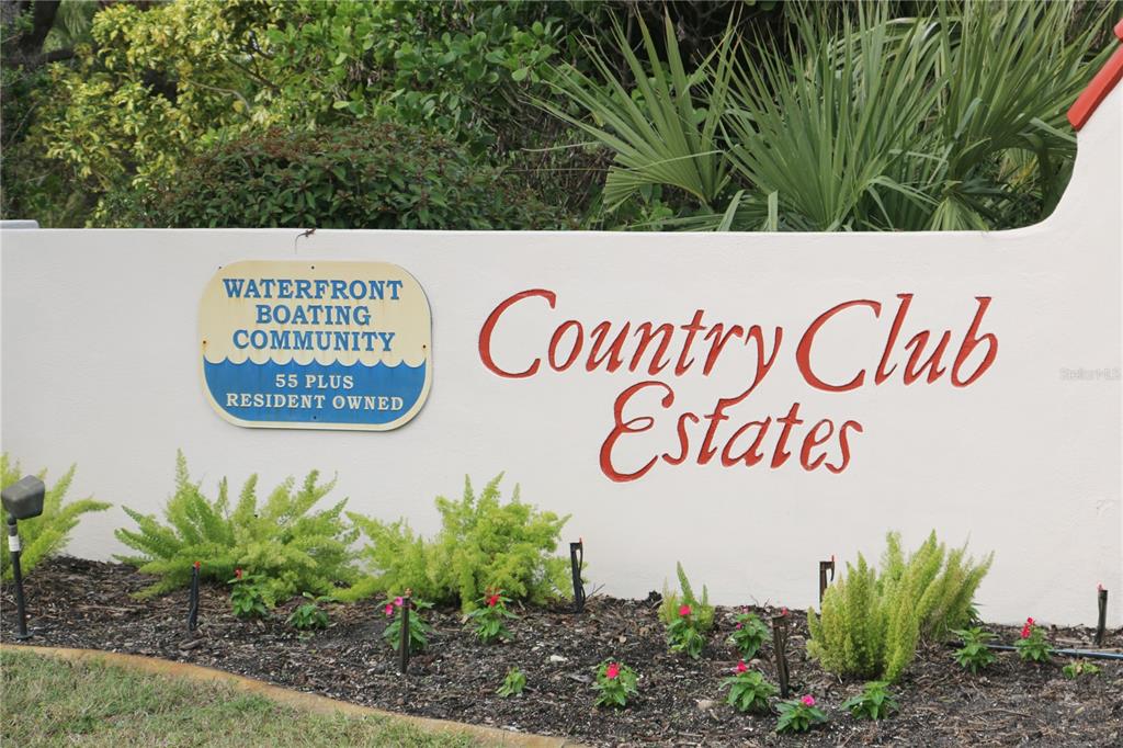 A white stucco wall features a sign for Country Club Estates and lush landscaping — 808 S GREEN CIRCLE, VENICE, FL