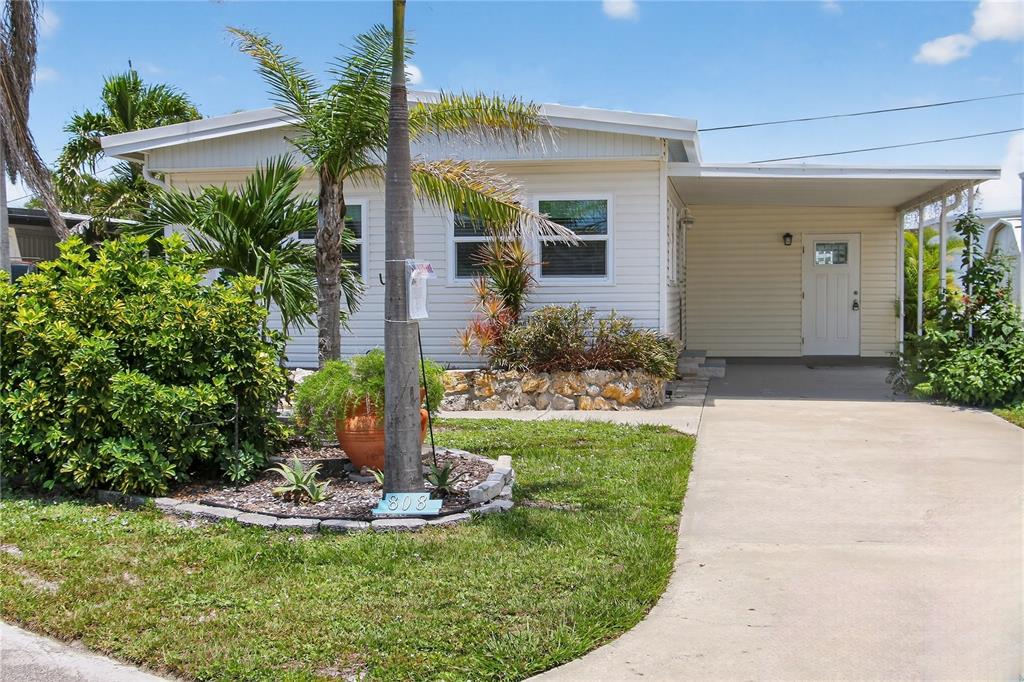A single-story mobile home with light siding, a palm tree, and a concrete driveway — 808 S GREEN CIRCLE, VENICE, FL