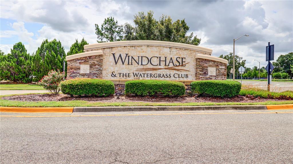 A stone monument sign for Windchase & The Watergrass Club sits in a landscaped area — 7651 WINDCHASE WAY, WESLEY CHAPEL, FL
