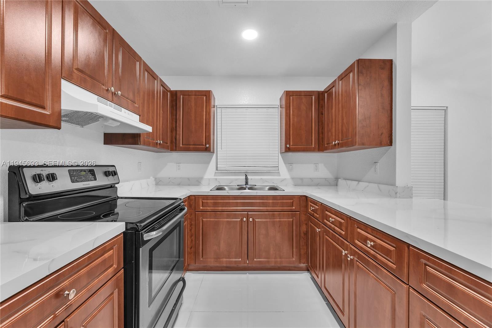 A kitchen features wood cabinets, white countertops, a black stove, and a stainless steel sink — 1541 NW 1st Ct, Miami FL 33136, MIAMI, FL