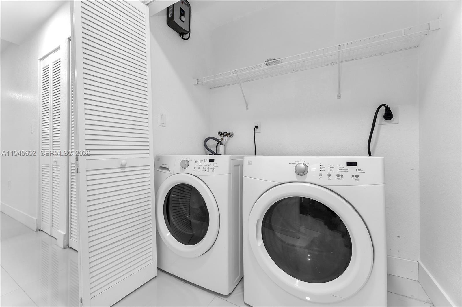 A laundry room features a white washer and dryer set beneath a wire shelf — 1541 NW 1st Ct, Miami FL 33136, MIAMI, FL