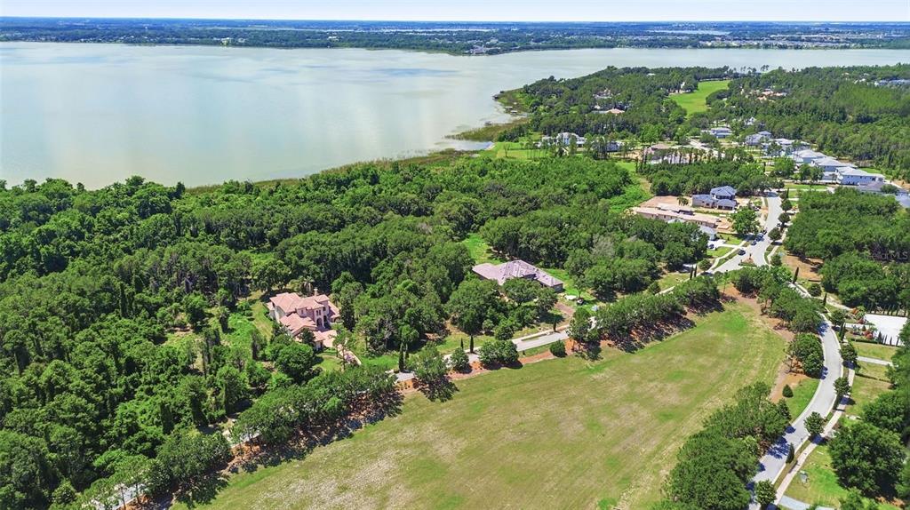 An aerial view shows a large house nestled in a wooded area near a lake — 17119 ETRUSCAN LANE, MONTVERDE, FL