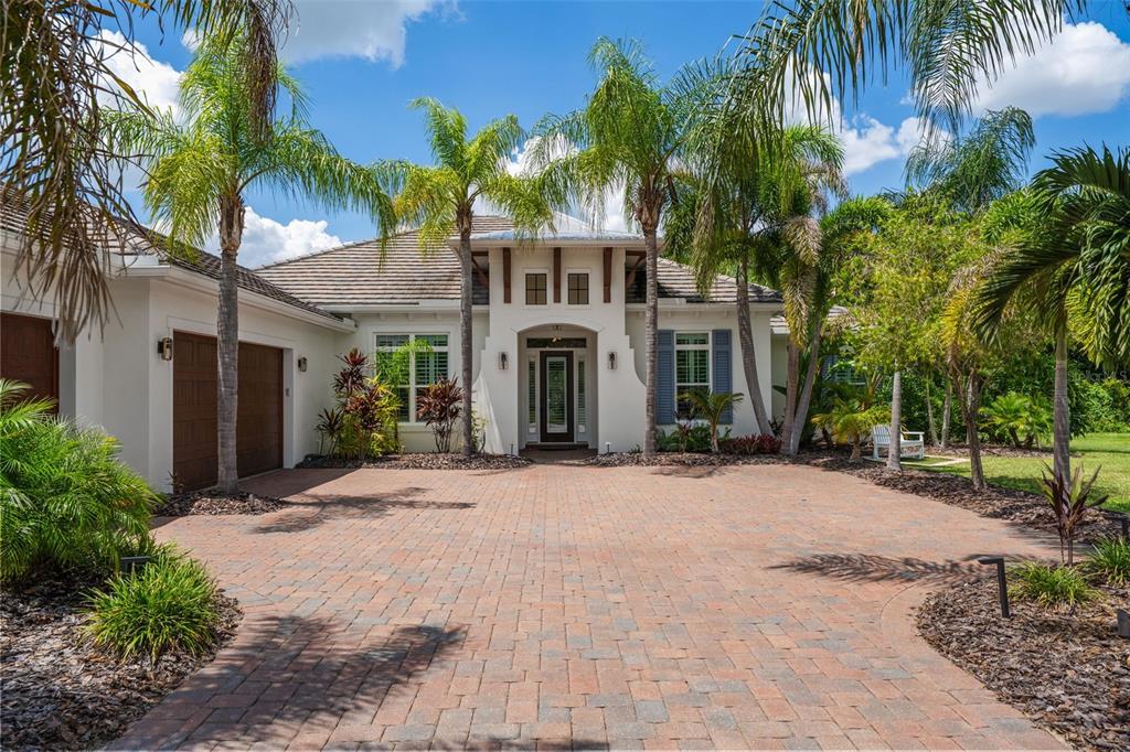 A single-story house with a paved driveway, palm trees, and a central arched entryway — 14205 9TH TERRACE NE, BRADENTON, FL