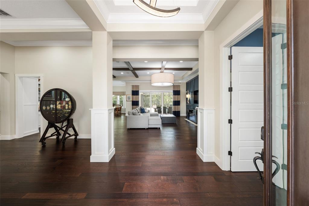 A view from an entryway into a living room with dark wood floors and columns — 14205 9TH TERRACE NE, BRADENTON, FL