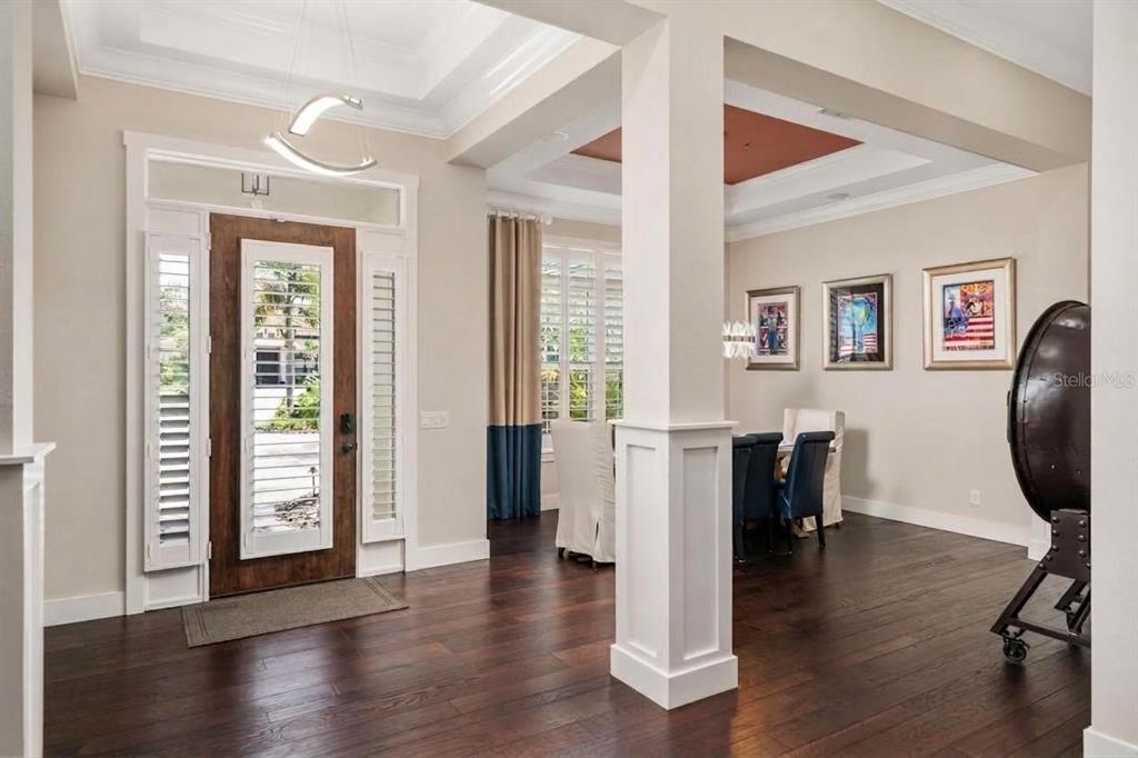 An entryway with dark wood floors, a wood-framed glass door, and a dining area beyond — 14205 9TH TERRACE NE, BRADENTON, FL