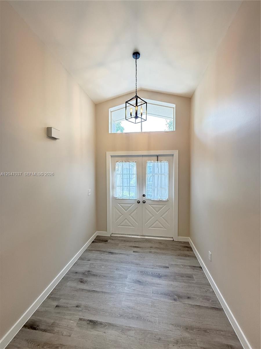 A high-ceilinged entryway features light-colored walls, wood-look flooring, and a double-door entrance — 10113 SW 223rd Ter, Cutler Bay FL 33190, CUTLER BAY, FL