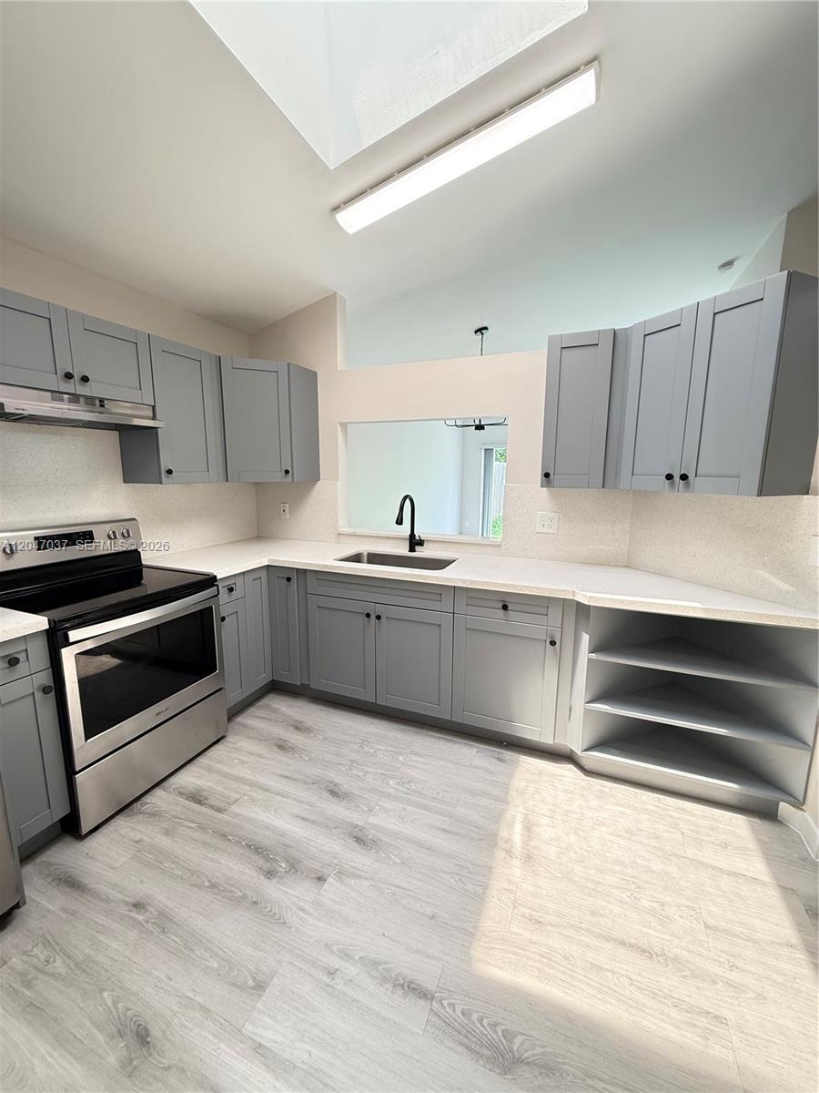 A kitchen features gray cabinets, stainless steel appliances, white countertops, and light wood-look flooring — 10113 SW 223rd Ter, Cutler Bay FL 33190, CUTLER BAY, FL