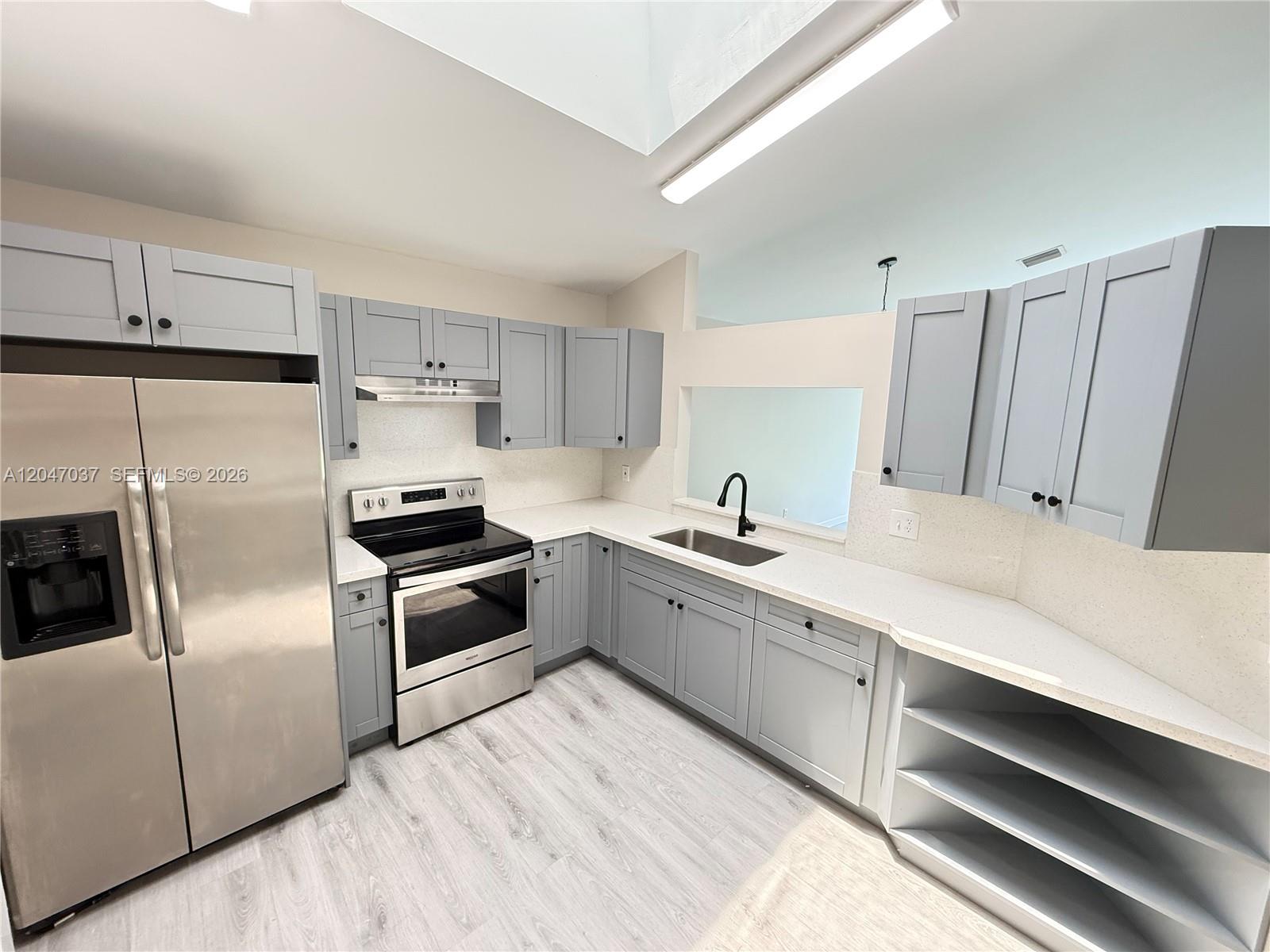 A kitchen features gray cabinets, stainless steel appliances, white countertops, and light wood-look flooring — 10113 SW 223rd Ter, Cutler Bay FL 33190, CUTLER BAY, FL