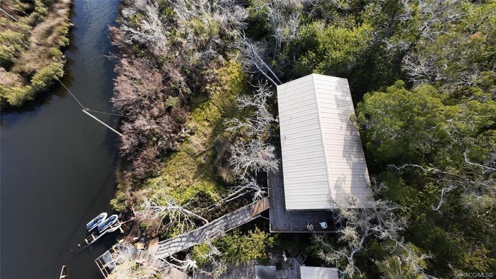 An aerial view shows a house with a metal roof nestled in trees beside a river — 5340 BLOUNT ISLAND, HOMOSASSA, FL