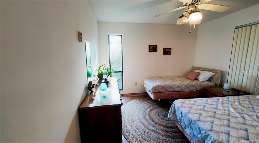 A bedroom features two beds, a wooden dresser, a round rug, and a ceiling fan — 5340 BLOUNT ISLAND, HOMOSASSA, FL