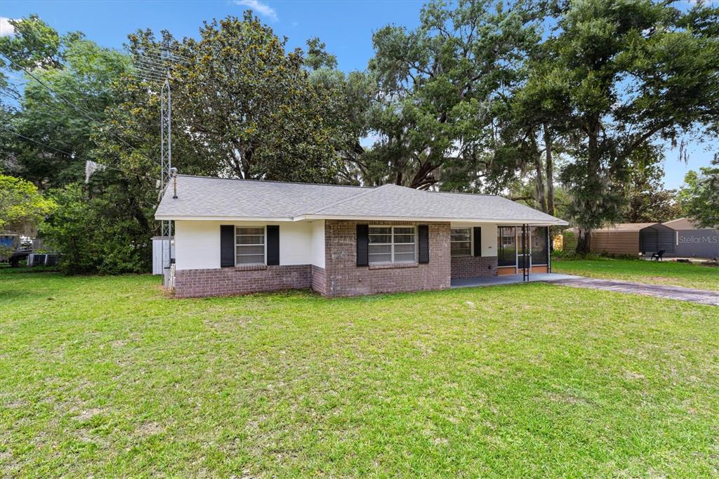 A single-story house with a brick and white exterior sits on a grassy lot — 603 MILRAY DRIVE, WILDWOOD, FL