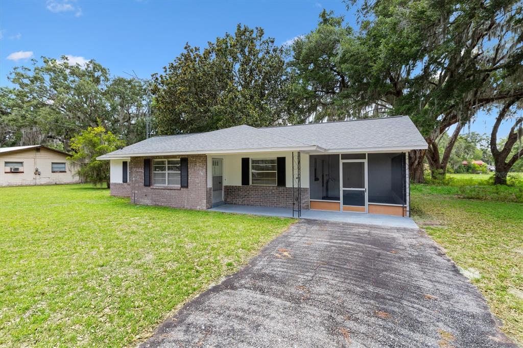 A single-story brick house with a screened-in porch and an asphalt driveway — 603 MILRAY DRIVE, WILDWOOD, FL