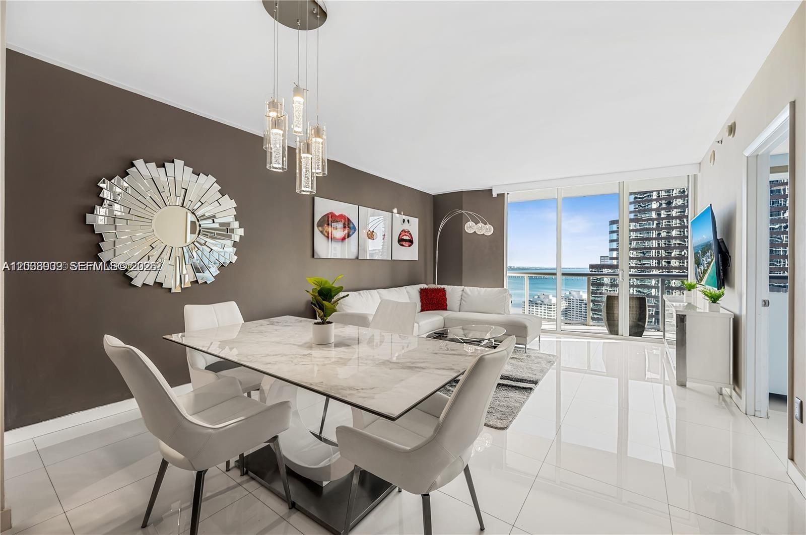 A modern dining and living area features a marble table, white chairs, and floor-to-ceiling windows — 485 Brickell Ave # 3109, Miami FL 33131, MIAMI, FL