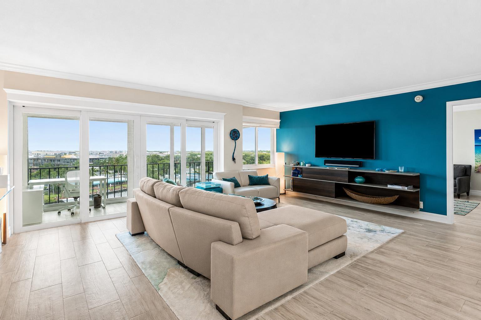A living room features a blue accent wall, a beige sectional sofa, and a balcony — 86 Macfarlane Drive # 8f, Delray Beach FL 33483, DELRAY BEACH, FL