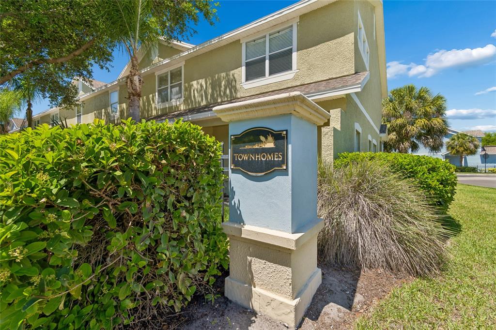 A light blue pillar with a townhomes sign stands in front of a tan building — 10925 WINTER CREST DRIVE, RIVERVIEW, FL