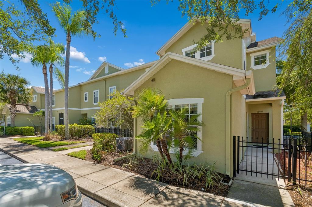 A two-story, light green stucco townhouse with a brown front door and palm trees — 10925 WINTER CREST DRIVE, RIVERVIEW, FL