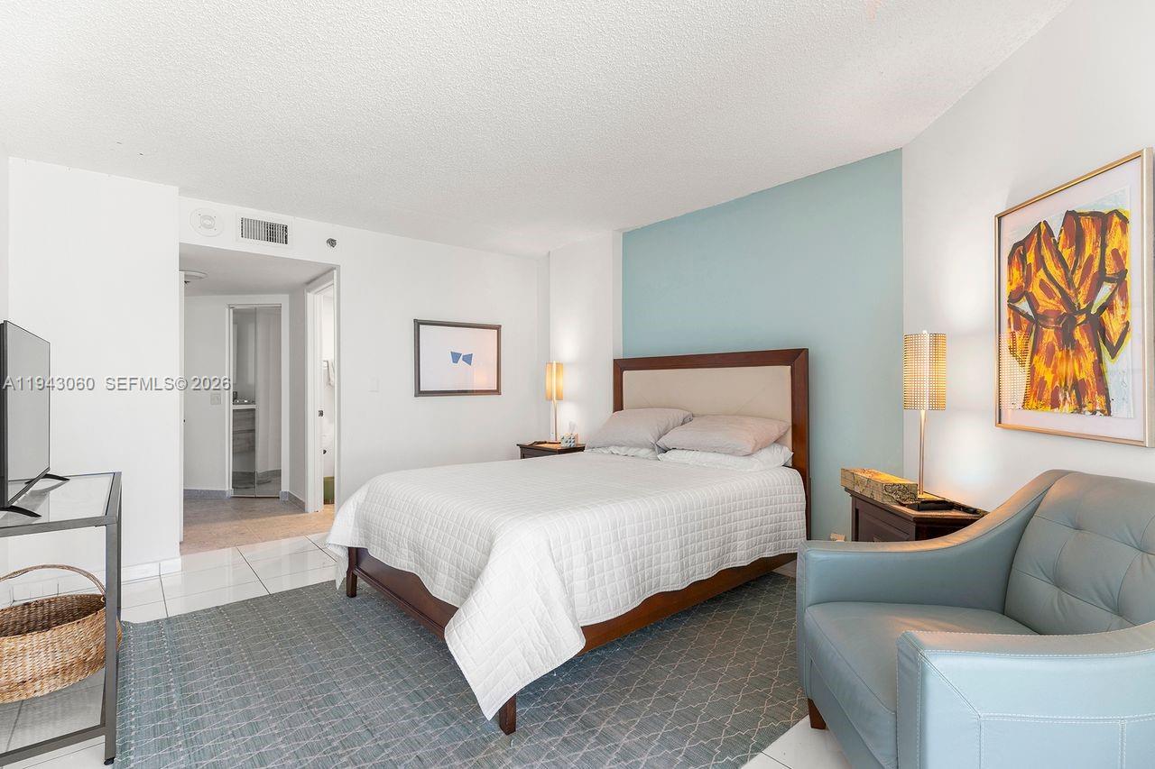A bedroom features a bed, a blue accent wall, and a blue armchair — 6767 Collins Ave # 1905, Miami Beach FL 33141, MIAMI BEACH, FL