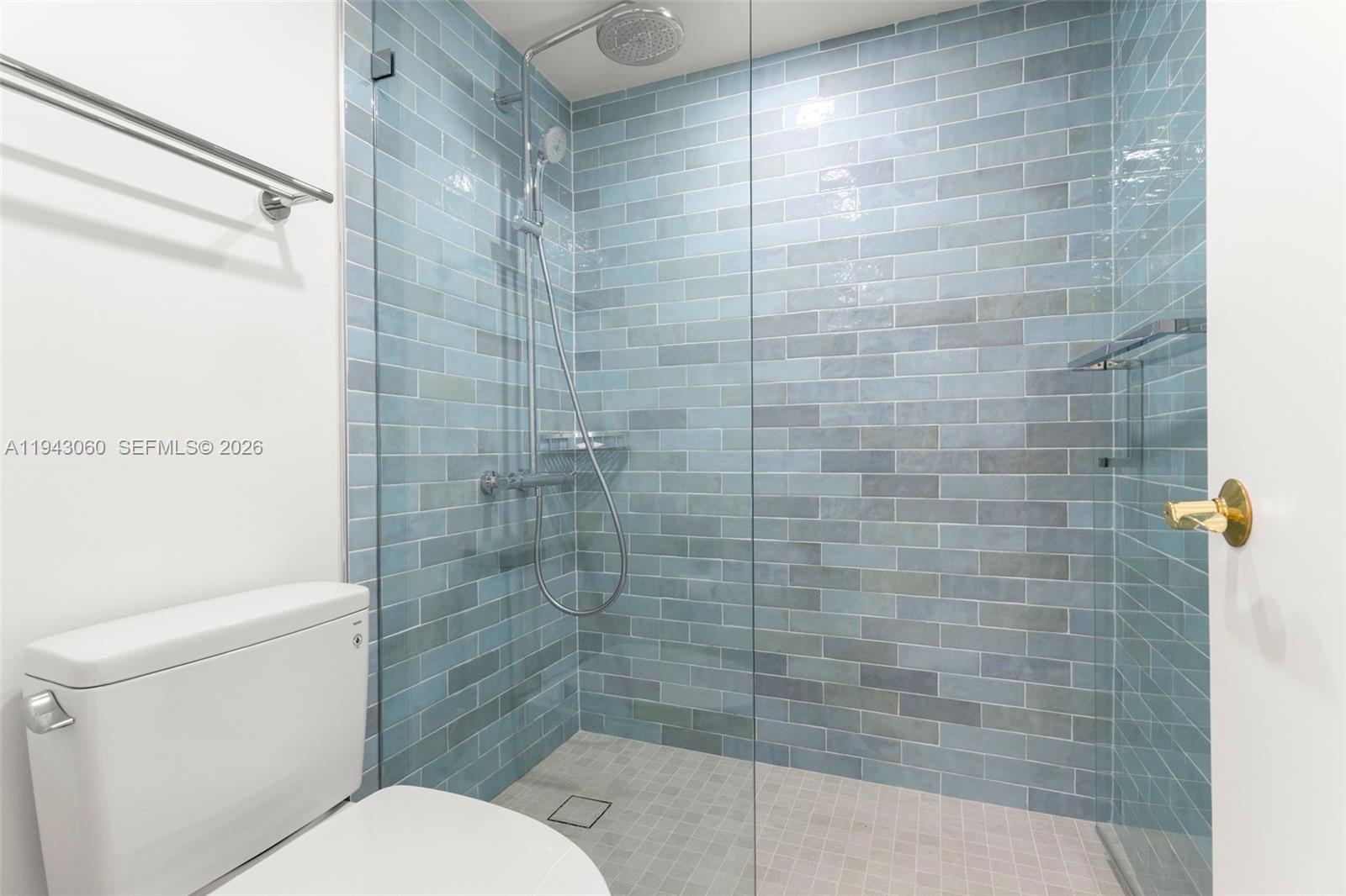 A bathroom features a glass-enclosed shower with blue subway tiles and a white toilet — 6767 Collins Ave # 1905, Miami Beach FL 33141, MIAMI BEACH, FL