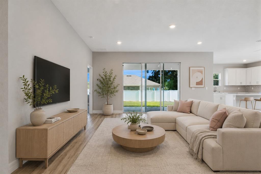 A living room with a sectional sofa, round coffee table, media console, and sliding glass doors — 4843 SW 131ST PLACE, OCALA, FL