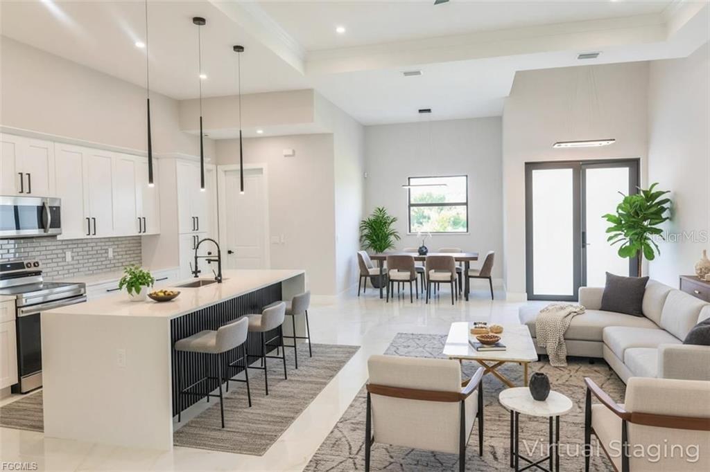 An open-concept kitchen, dining area, and living room with white cabinetry and modern furniture — 3512 9TH STREET W, LEHIGH ACRES, FL