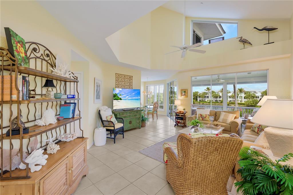 A bright living room with high ceilings, tile floors, wicker furniture, and a water view — 760 SEABOARD LINE LANE, BOCA GRANDE, FL