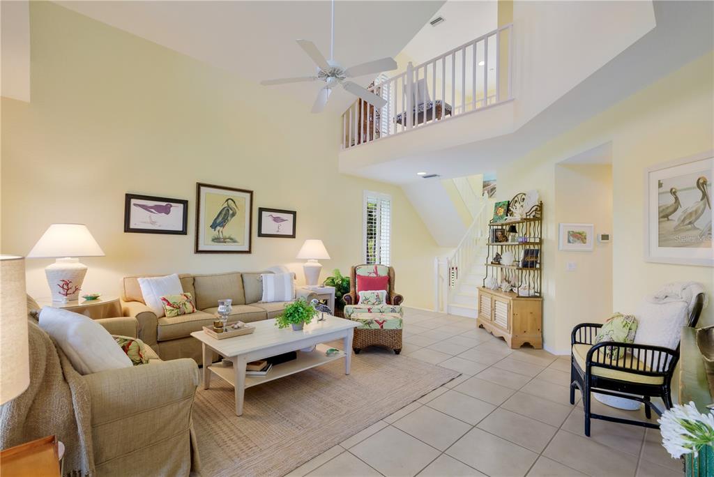 A living room with a vaulted ceiling, loft, staircase, and light-colored tile flooring — 760 SEABOARD LINE LANE, BOCA GRANDE, FL