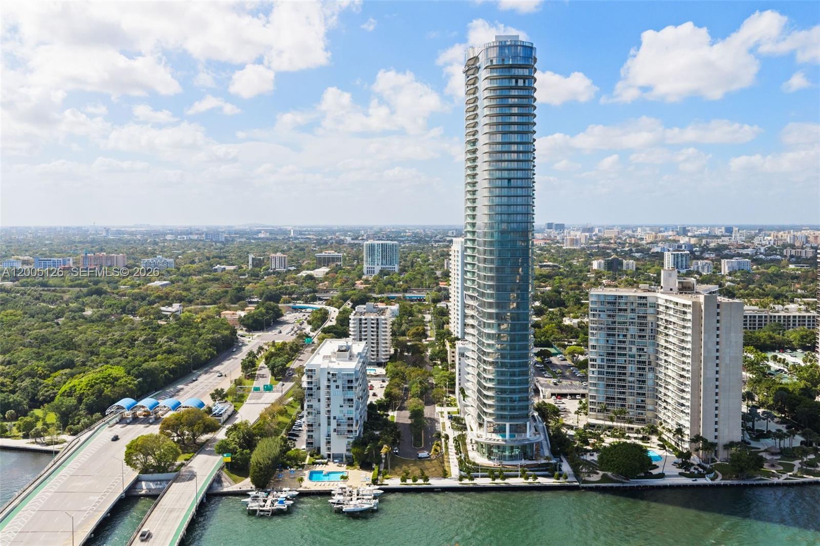 An aerial view shows a tall glass residential tower surrounded by smaller buildings and water — 175 SE 25 RD # 2604, Miami FL 33129, MIAMI, FL