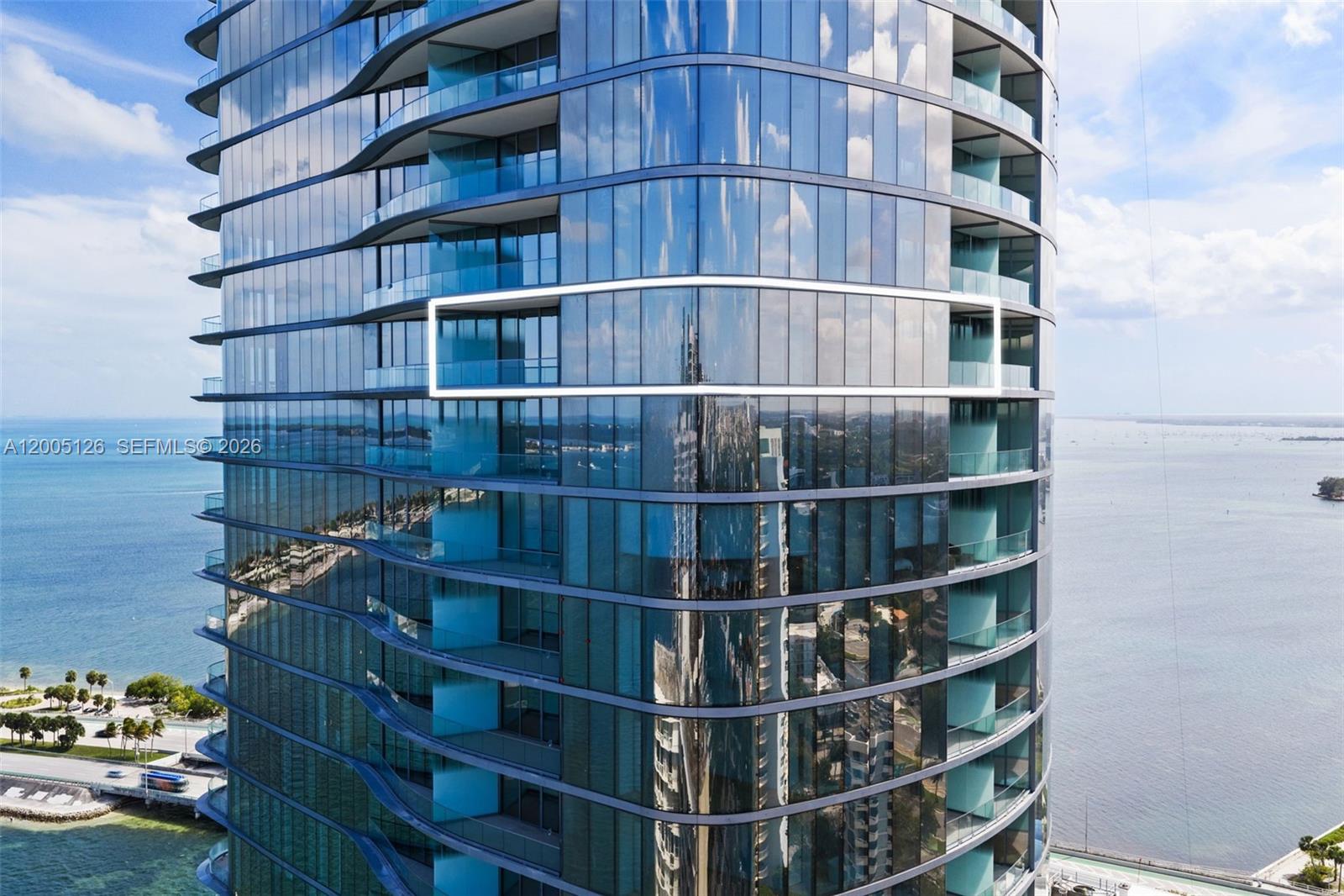 An exterior view of a modern glass high-rise building featuring curved balconies and floor-to-ceiling windows — 175 SE 25 RD # 2604, Miami FL 33129, MIAMI, FL