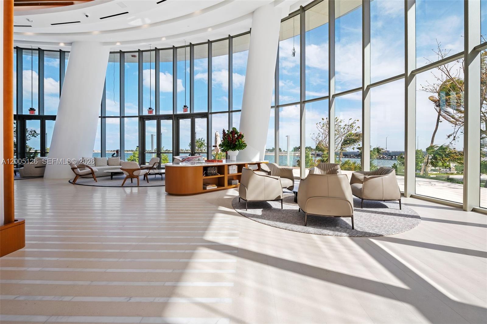 A bright, modern lobby features floor-to-ceiling windows, white tiled floors, and multiple seating areas — 175 SE 25 RD # 2604, Miami FL 33129, MIAMI, FL