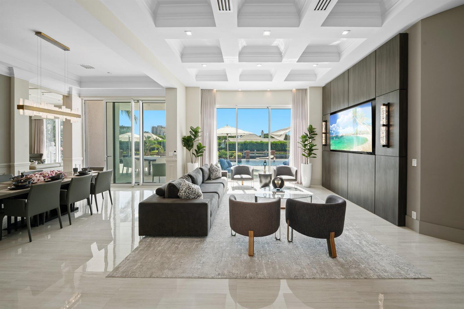 A modern living and dining area features a coffered ceiling, tile floors, and pool views — 81 S Island Dr, Ocean Ridge FL 33435, OCEAN RIDGE, FL