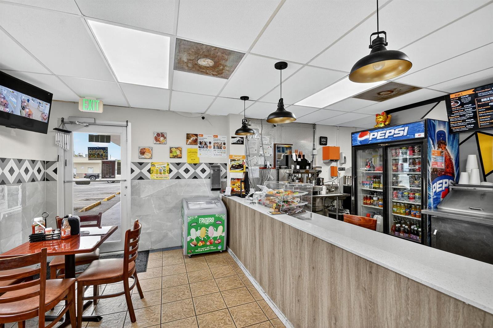 A small restaurant interior features a service counter, a Pepsi refrigerator, and dining tables — 1541 W Blue Heron Boulevard, Riviera Beach FL 33404, RIVIERA BEACH, FL